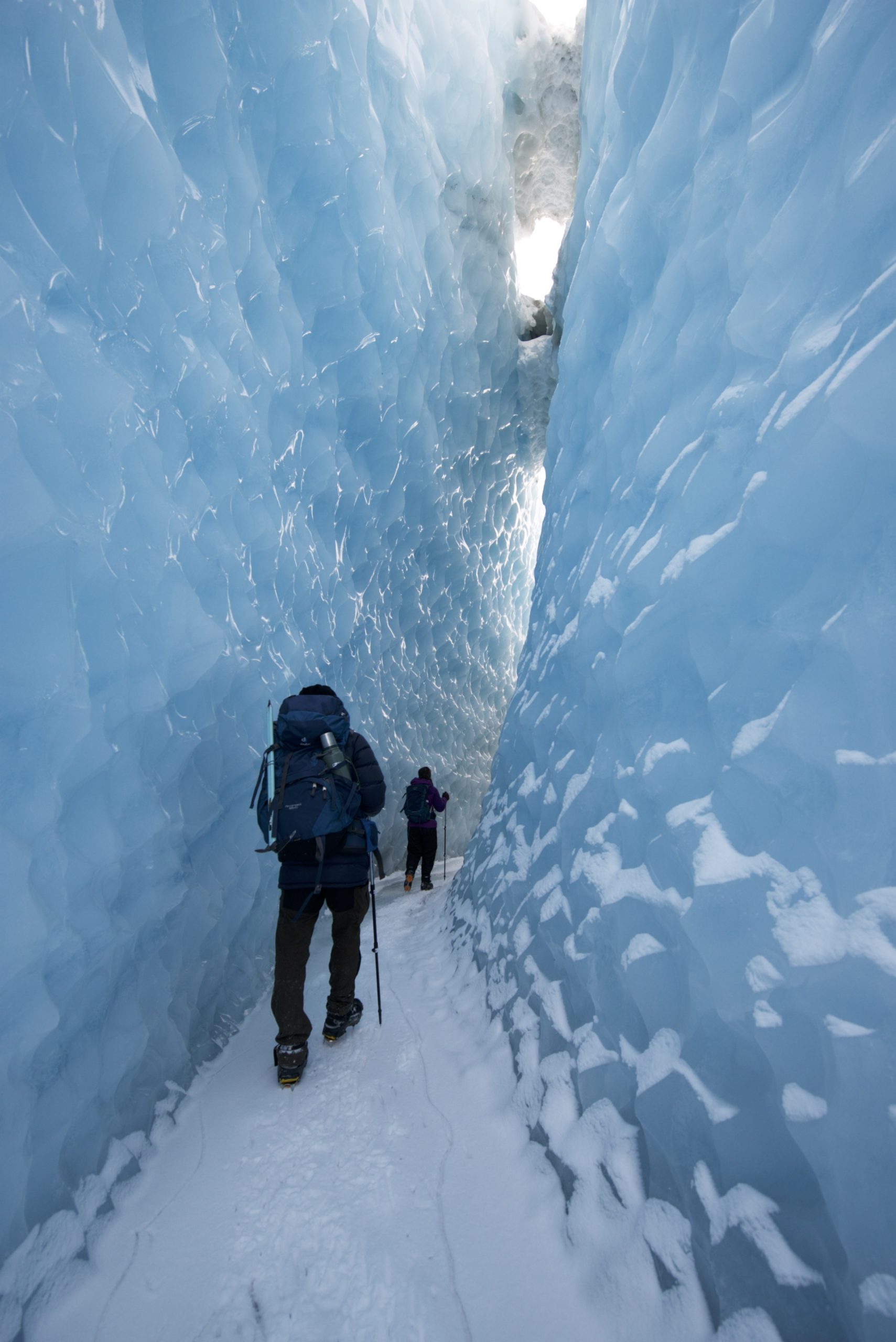 Climbers walk through between steep cliff inside of the glacier Greenland