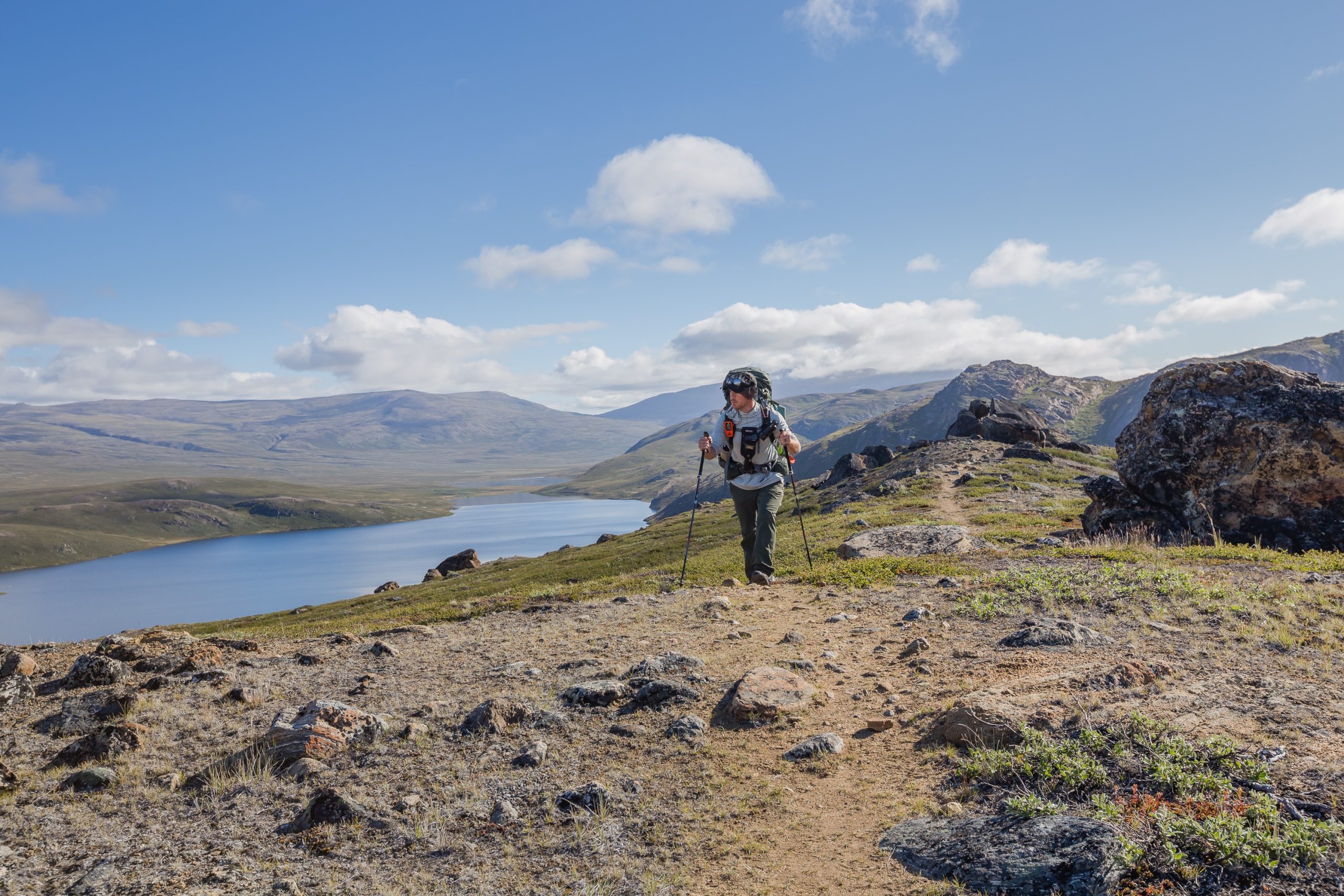 Male hiker navigates mountainous terrain on the Arctic Circle Trail after leaving Ikkattooq Hut